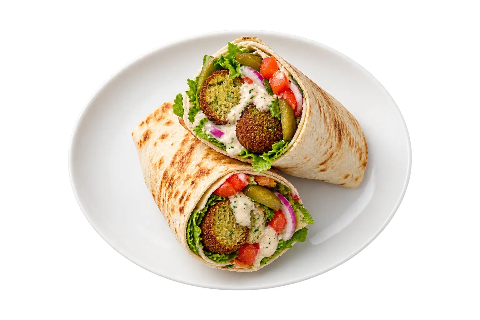 Falafel wrap halves with tahini, lettuce, tomato and pickles on a white ceramic plate